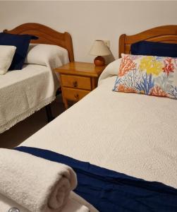 拉科萨Apartamento Raxobrisamar的一间卧室设有两张床和木制床头柜