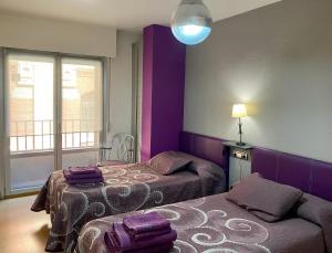 潘普洛纳贝利亚公寓的紫色的客房配有两张床和一盏灯。