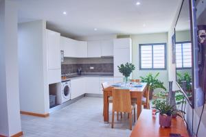 圣玛丽亚Lc Apartments - Sunrise的厨房配有白色橱柜和桌椅