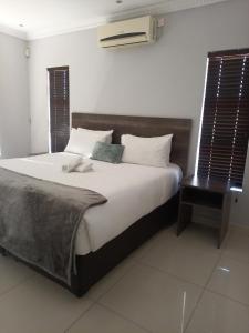 哈博罗内Olive Exclusive的一间卧室配有一张大床和木制床头板