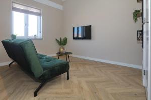 诺德韦克appartement-gratis parkeren -bij strand en in het centrum的客厅配有绿色椅子和电视