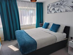 大德里菲尔德Benjamin Gardens Holiday Home的一间卧室配有一张带蓝色窗帘的大床