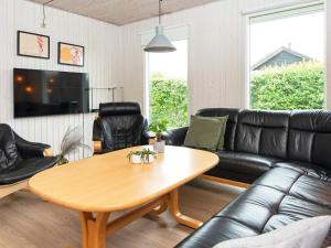森讷比9 person holiday home in Juelsminde的客厅配有黑色真皮沙发和桌子
