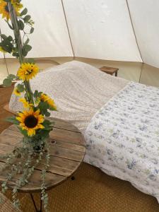 Upper HulmeBluebell bell tent The Roaches的帐篷旁的桌子上摆放着向日葵花瓶