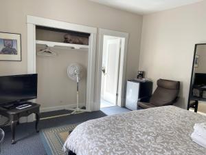 温哥华道格拉斯住宿加早餐旅馆的一间卧室配有一张床、一台电视和一把椅子