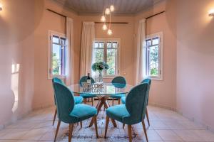 ParalíaSunset English Villas的一间设有玻璃桌和蓝色椅子的用餐室