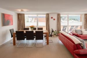 采尔马特粉雪公寓的客厅配有桌子和红色沙发