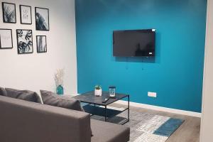 OsnyTulsa Home - Appartement 2 chambres, Charmant et moderne avec terrasse privée的带沙发和蓝色墙壁的客厅