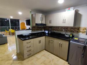 麦德林Apartamento en Laureles con Excelente Ubicación的厨房配有白色橱柜和黑色台面