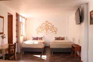 阿亚库乔Astromelia Hotel的一间卧室设有两张床、一张桌子和一个窗口