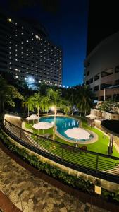 名古屋Grand Eska Hotel & Suites Batam的夜间公园内一个带遮阳伞的游泳池