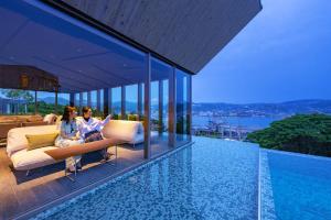 长崎长崎花园度假大酒店的两个女人坐在一个带游泳池的房子里的沙发上