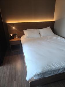 釜山Elbon The Stay的一张配有白色床单和床头柜的大床