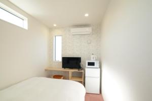 立山町Hotel Cradle Cabin Tateyama的卧室配有白色的床和电视。