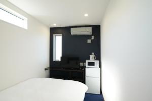 立山町Hotel Cradle Cabin Tateyama的卧室配有白色的床和微波炉