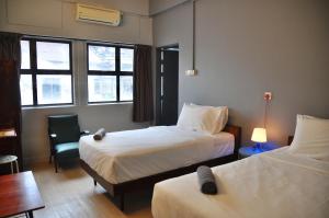 怡保GRAYHAUS INN Ipoh的酒店客房,配有两张床和椅子