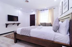纳纽基Arabel's Place Riverside Villas的卧室配有一张白色大床和电视。