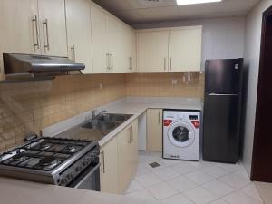 拉斯阿尔卡麦Hala Holiday Homes- Bab Al Bahr Residence, Al Marjan Island的厨房配有水槽、炉灶和洗碗机