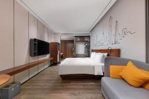 深圳深圳车公庙逸扉酒店的一间卧室配有一张床、一台电视和一张沙发