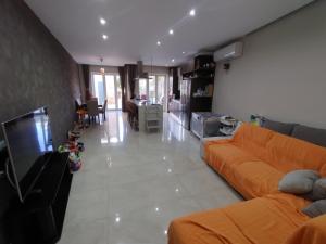 KirkopThe Luxury Home - Next to airport!的一间带橙色沙发的客厅和一间厨房
