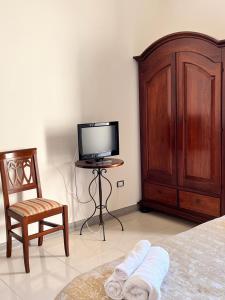 帕尔米B&B Andromeda的一间卧室配有一张床、一台电视和一把椅子