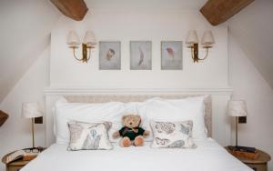 上斯劳特村君王酒店的泰迪熊坐在床上,床上有枕头