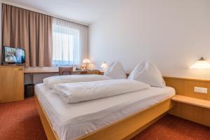 格拉茨克恩布阿姆酒店的酒店客房带一张大床,带白色床单