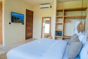 龙目岛库塔Olea Villas Resort的卧室配有白色的床和电视