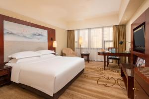深圳深圳阳光酒店的酒店客房设有一张白色大床和一张书桌