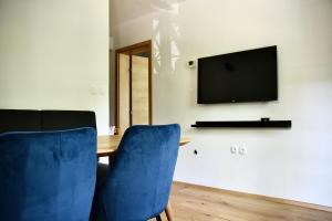 博德森特克Olimian Oasis Village Lipa 107的一张桌子,上面有两把蓝色的椅子和墙上的电视