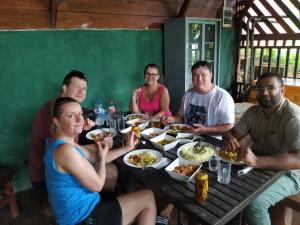 代尼耶耶Rainforest View Hostal And Rainforest Tours的一群坐在桌子旁吃食物的人