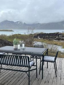 LyngværetLuksushytte med Jacuzzi, Summer&Winter Retreat的水景甲板上的桌椅