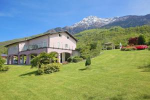 科利科Legnoncino Holiday Home- Lake Como的一座大房子,位于一个绿地,后面有群山