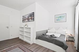 腓特烈港Appartment Maria Friedrichshafen Bodensee的白色卧室设有床和架子