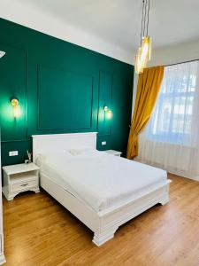 奥拉迪亚Sí Apartments Aquapark的卧室配有白色的床和绿色的墙壁