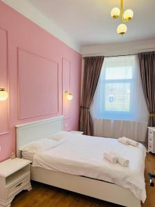 奥拉迪亚Sí Apartments Aquapark的卧室配有一张带粉红色墙壁的大床
