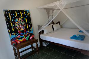 南威Cocolala Beach House的卧室配有一张床,墙上挂有绘画作品