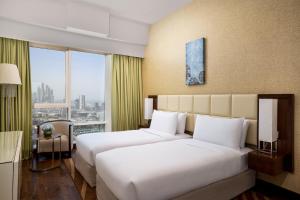 迪拜La Suite Dubai Hotel & Apartments的酒店客房设有两张床和窗户。