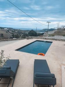 斯希努萨岛Sohoros Luxury Suites的庭院内的游泳池,配有两把椅子