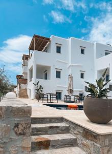 斯希努萨岛Sohoros Luxury Suites的一座白色的大建筑,前面设有一个庭院