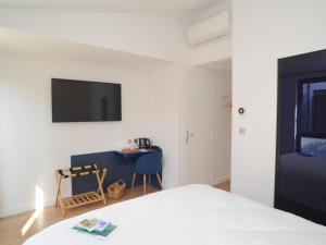 滨海拉库阿尔德Hôtel Les Mouettes的一间卧室配有一张床、一张书桌和一台电视。