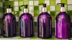 马斯喀特阿曼森特马斯喀特酒店的四个紫色洗发水瓶子,放在架子上