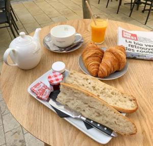 滨海拉库阿尔德Hôtel Les Mouettes的一张桌子,上面放着一盘面包、羊角面包和橙汁