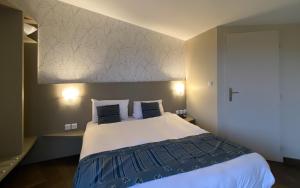 蒙贝利亚尔Charme Hôtel et Spa, Montbéliard Sud的一间卧室配有一张带蓝白色床单的大床