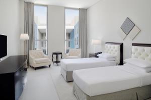 迪拜Delta Hotels by Marriott Dubai Investment Park的酒店客房设有两张床和一台平面电视。