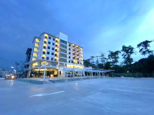 春武里GEEN Hotel Chonburi的一座大型建筑,前面设有停车场