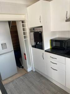 布特尔3 Bed Sleep 6, Bootle/Aintree的厨房配有白色橱柜和微波炉