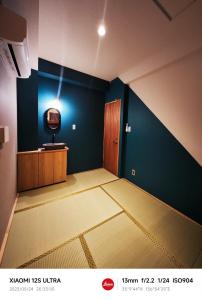 名古屋2023年6月開業 サカエ ゲストハウス的一间空房间,蓝色的墙上配有电视
