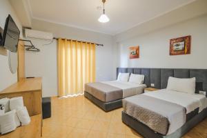 卡萨米尔Hotel Milo Ksamil的酒店客房设有两张床和一台平面电视。