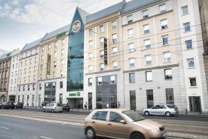 弗罗茨瓦夫B&B HOTEL Wrocław Centrum的一辆棕褐色汽车在建筑物前的街道上行驶